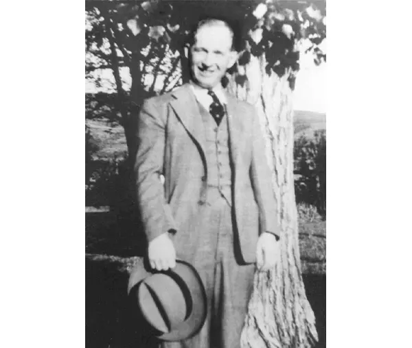 A man in suit and tie holding a hat.