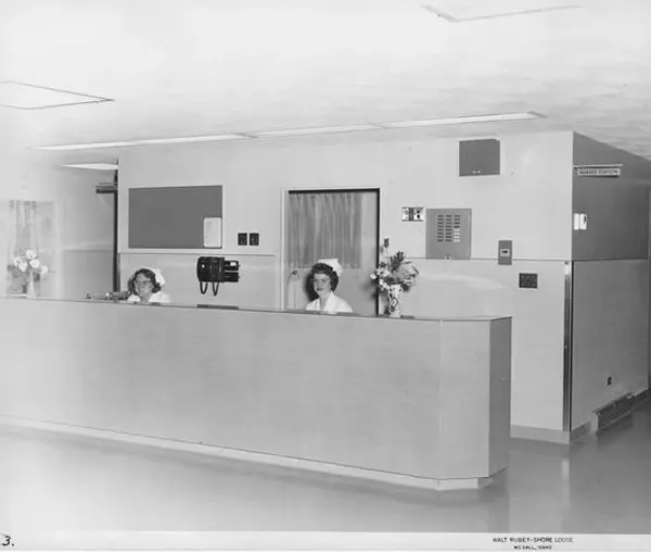 Three women are sitting at a counter in an office.