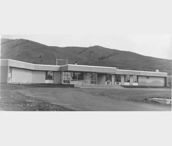 A black and white photo of a building with mountains in the background.