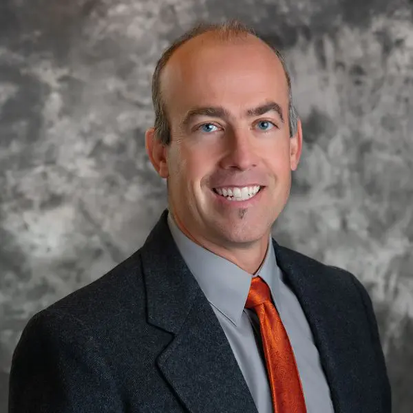 A man in a suit and tie smiling for the camera.