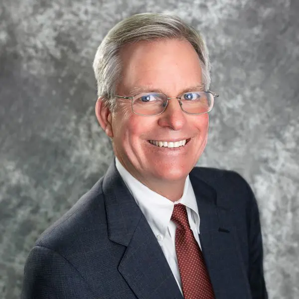 A man in a suit and tie smiling for the camera.