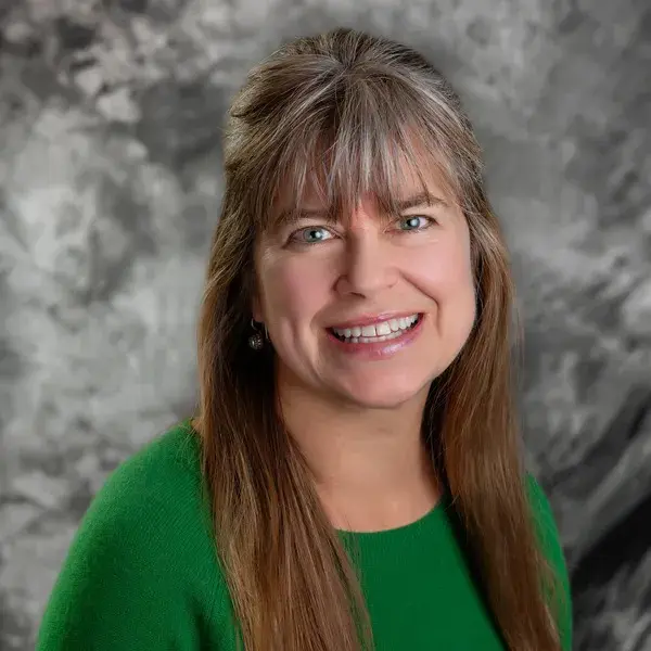 A woman in green shirt smiling for the camera.