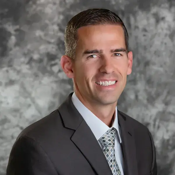 A man in suit and tie smiling for the camera.