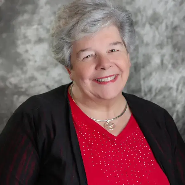 A woman with grey hair wearing a red shirt.